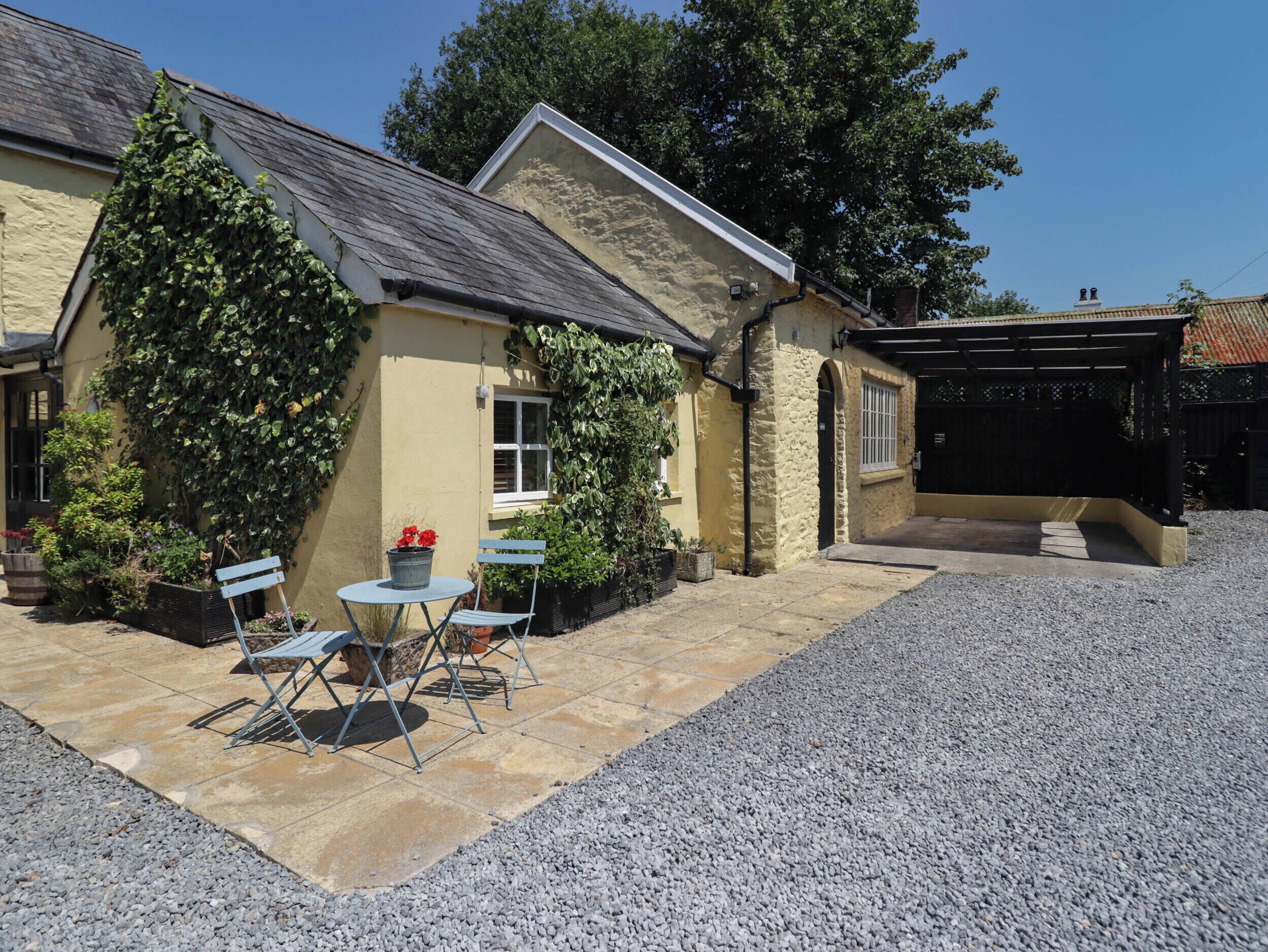 A stone house with a gravel driveway and a covered patio area.