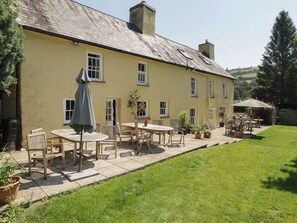 A yellow building with a patio area featuring outdoor seating and potted plants. - Ty Mawr Country House (Carmarthen)