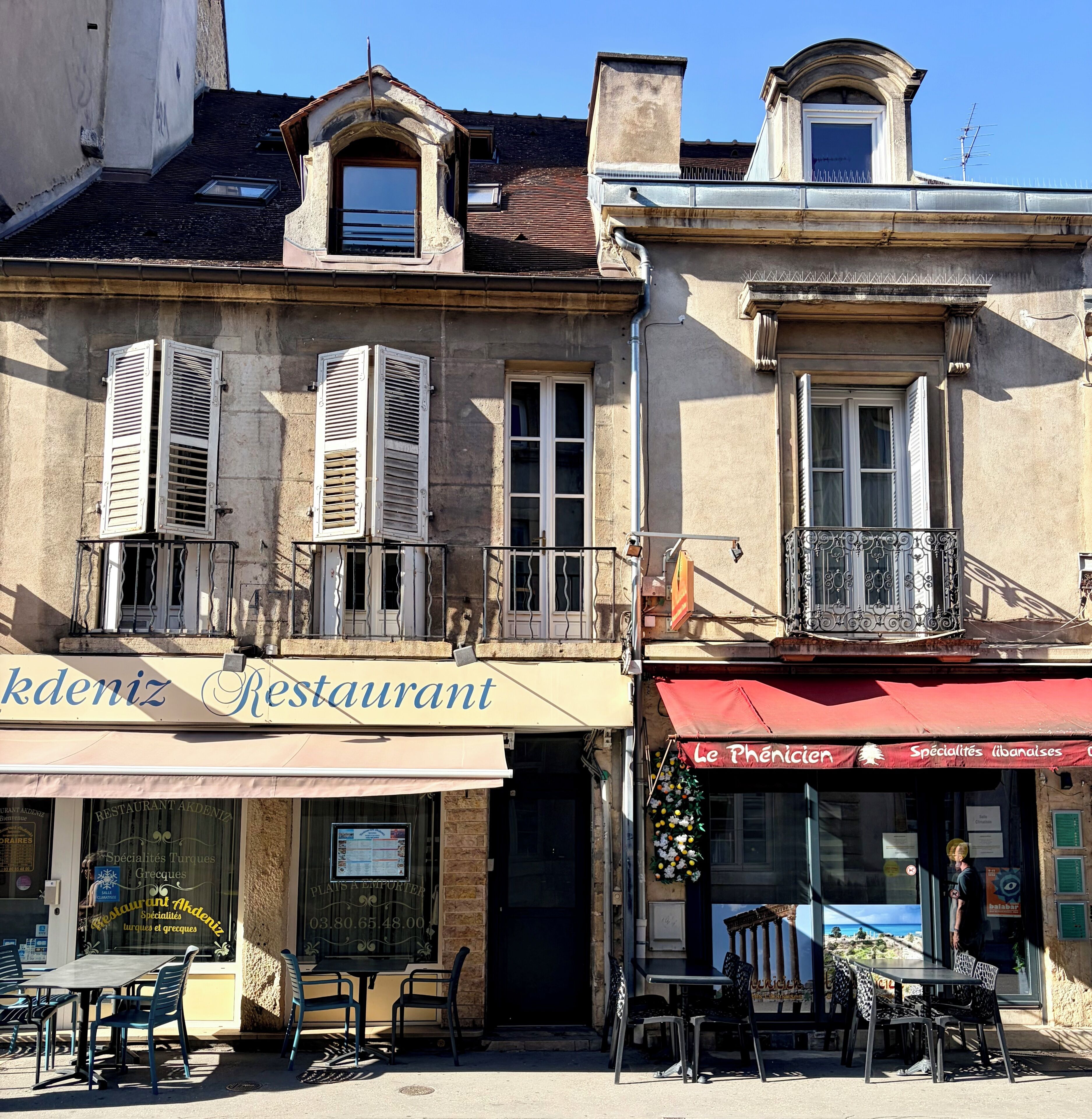 Ein Restaurant mit Außenbereich, einem Balkon und einem Schild mit der Aufschrift 'Le Phénicien'.