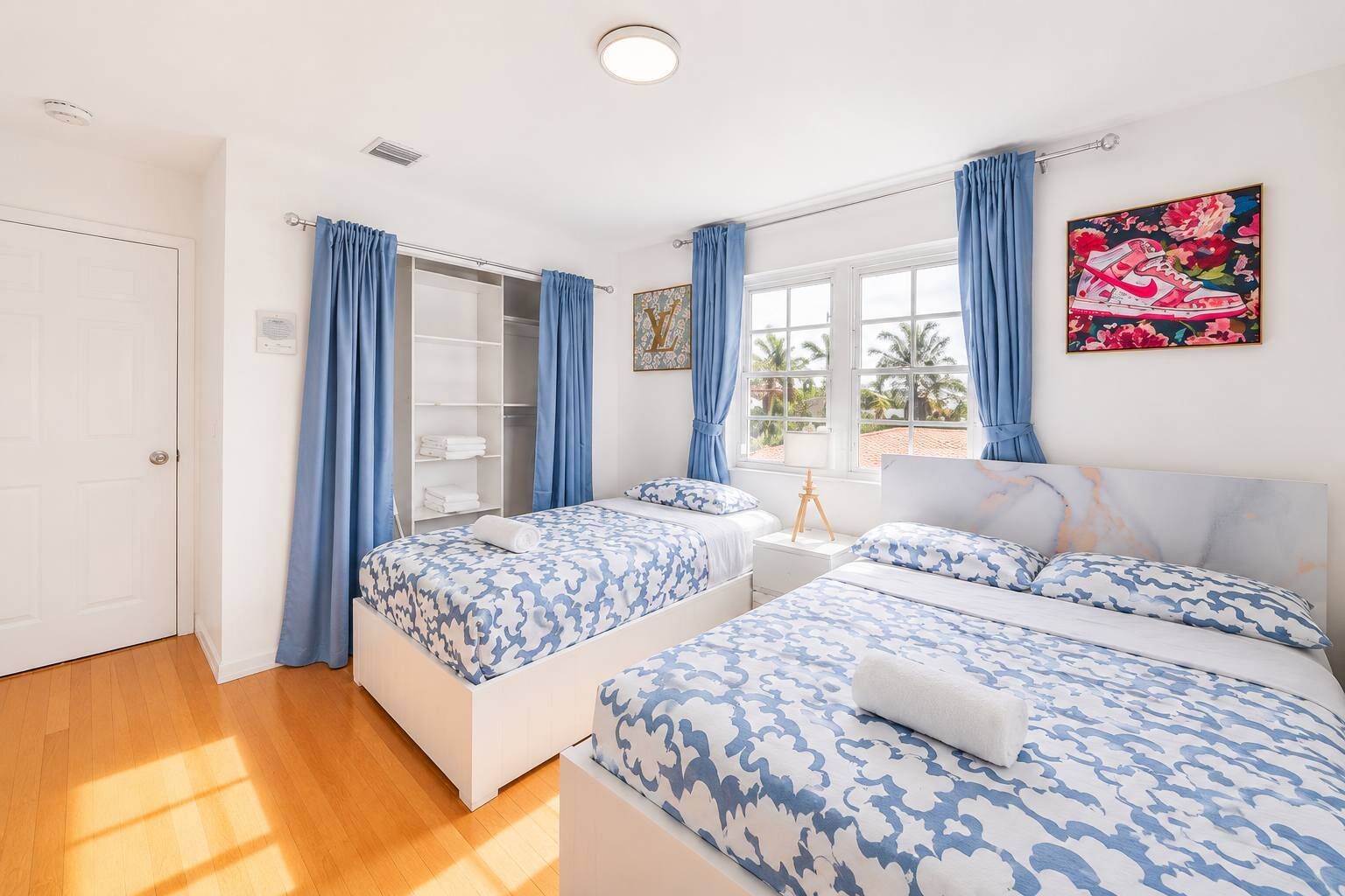 A bedroom with two beds, a wardrobe, and a window with curtains.