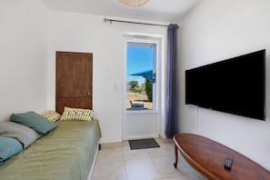 Ein Schlafzimmer mit Bett, einem Holzschrank, einem Fernseher und Blick durch eine Tür.