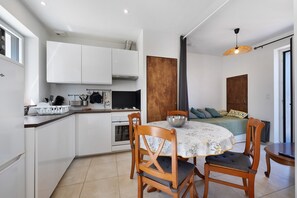 Una cocina compacta con armarios blancos, una estufa y un comedor con una mesa redonda y dos sillas.