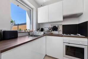 Eine moderne Küche mit weißen Schränken, einem Einbauofen und einem Fenster für natürliches Licht.