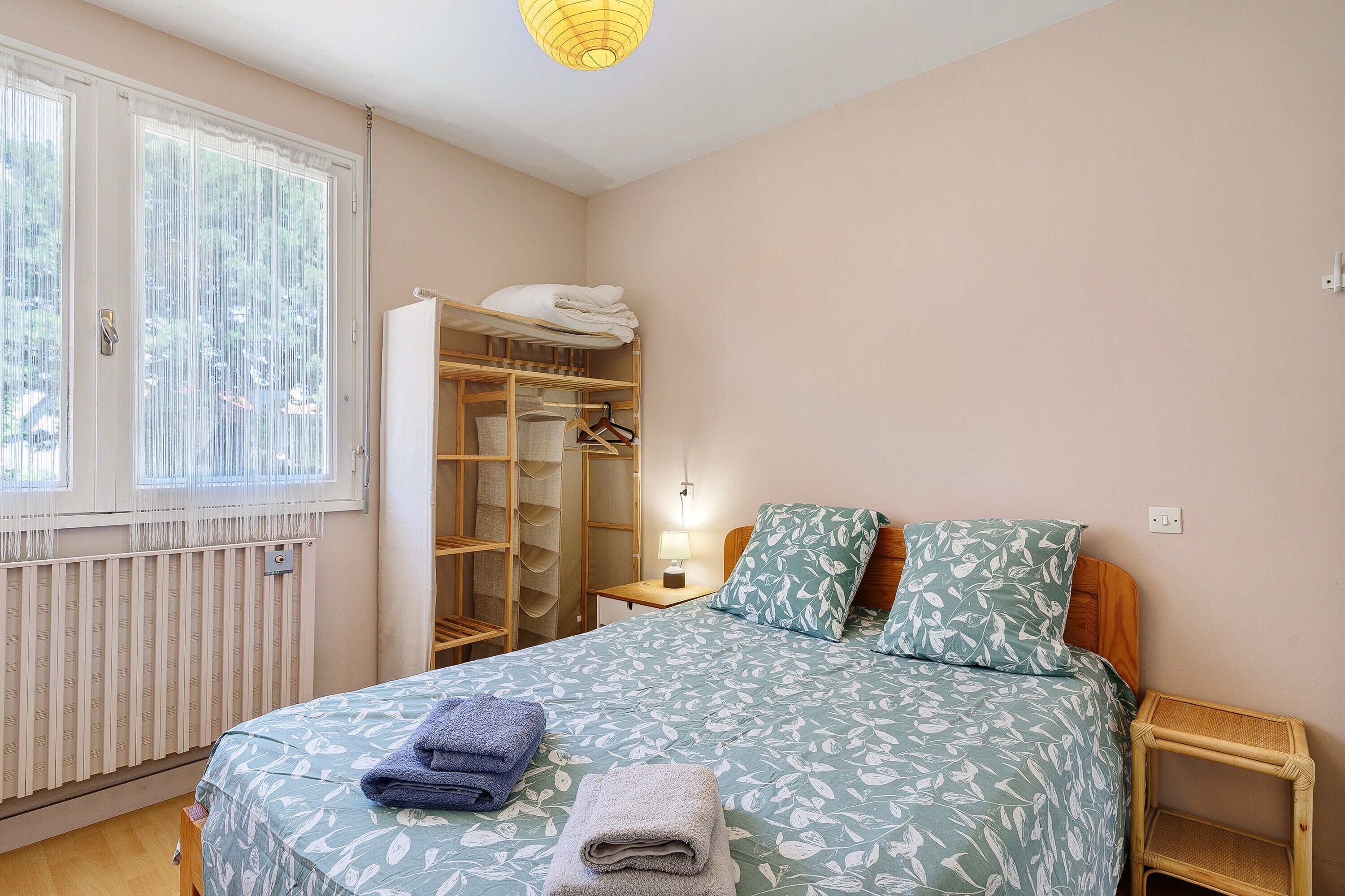 Une chambre à coucher avec un lit, une armoire, une table de chevet et une fenêtre.