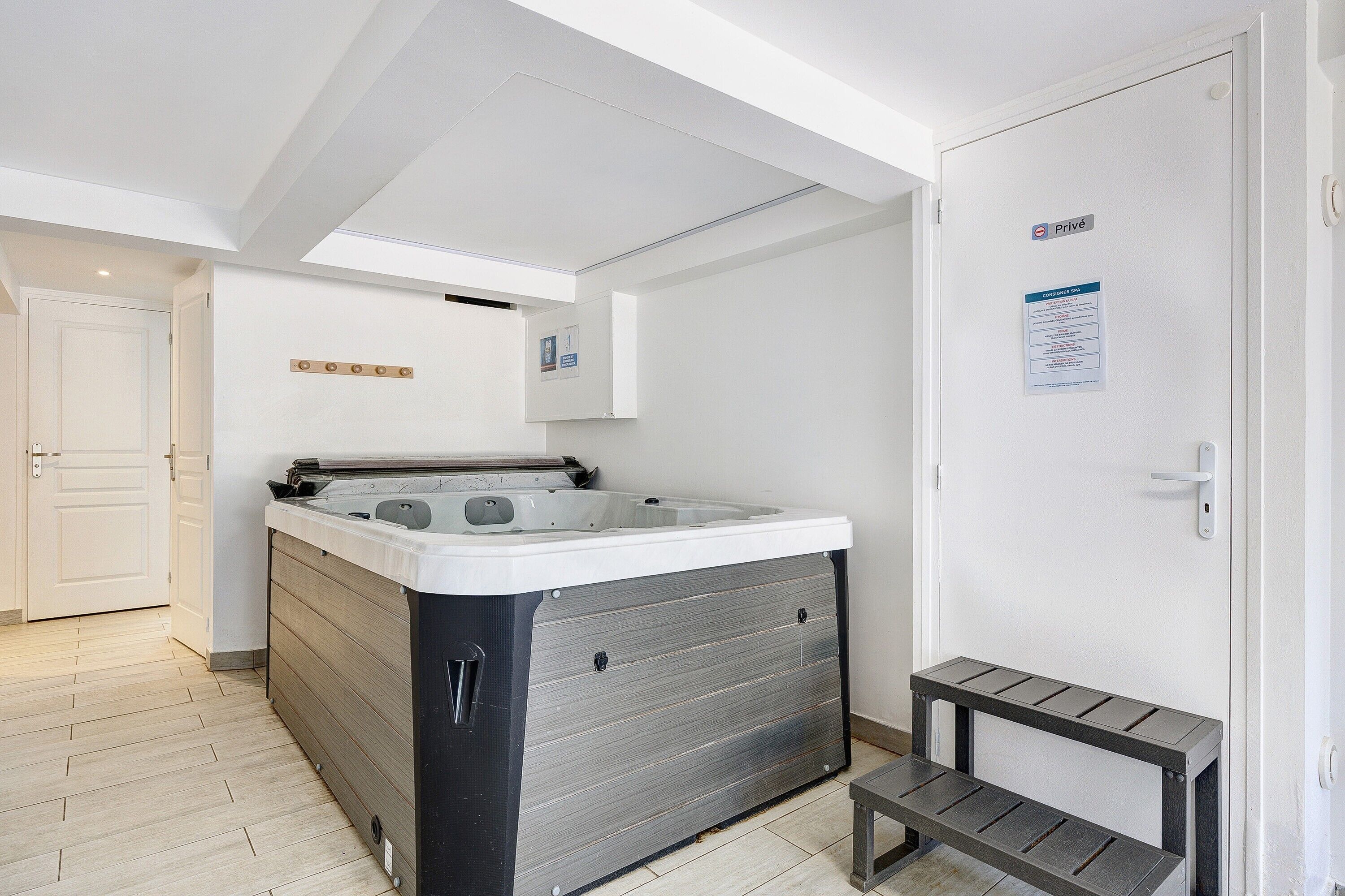 Un bagno moderno con una grande vasca, una zona doccia e un piccolo sedile.