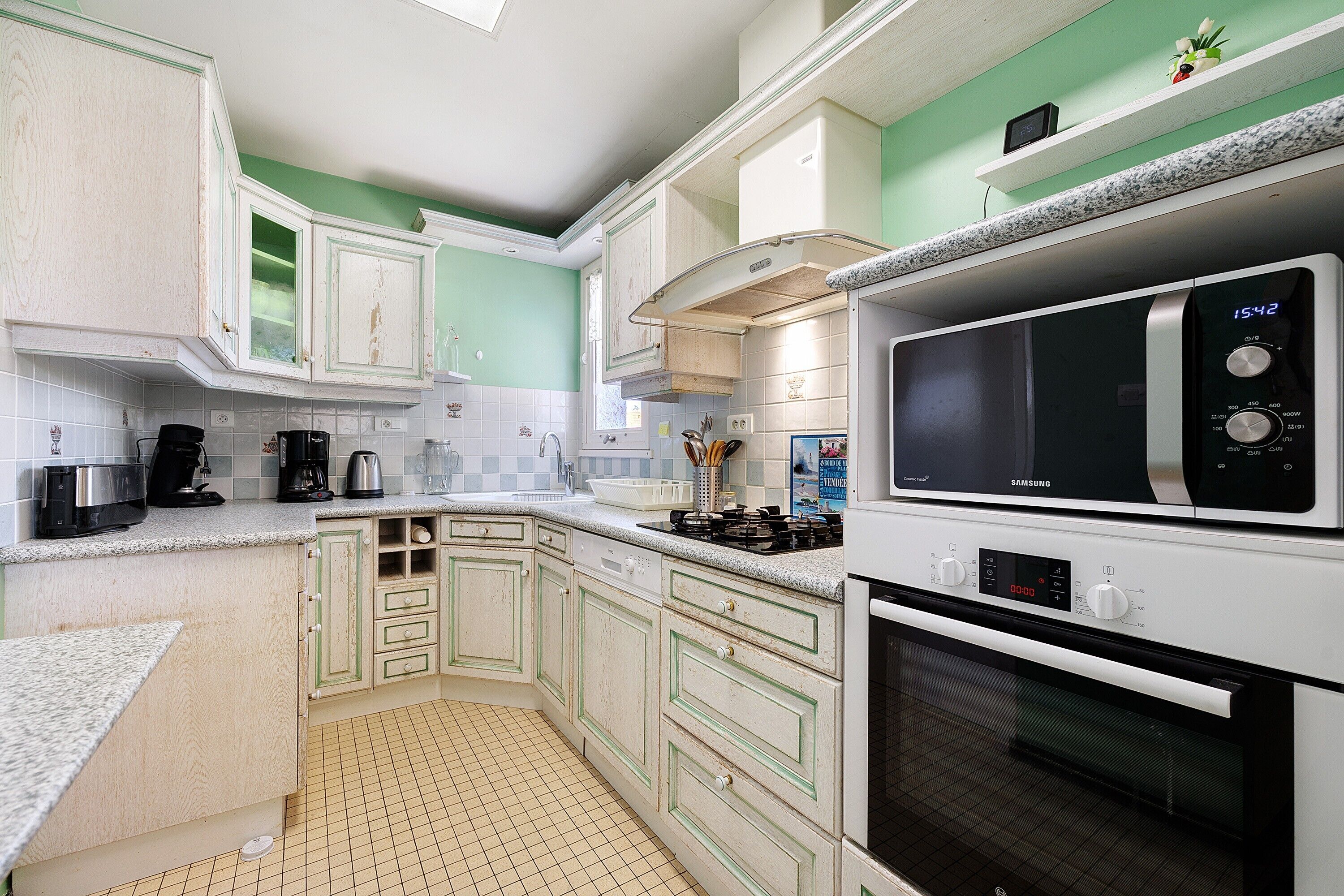 Una cucina con mobili bianchi, un forno a microonde e un piano cottura.