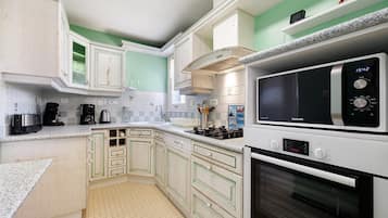Una cucina con mobili bianchi, un forno a microonde e un piano cottura.