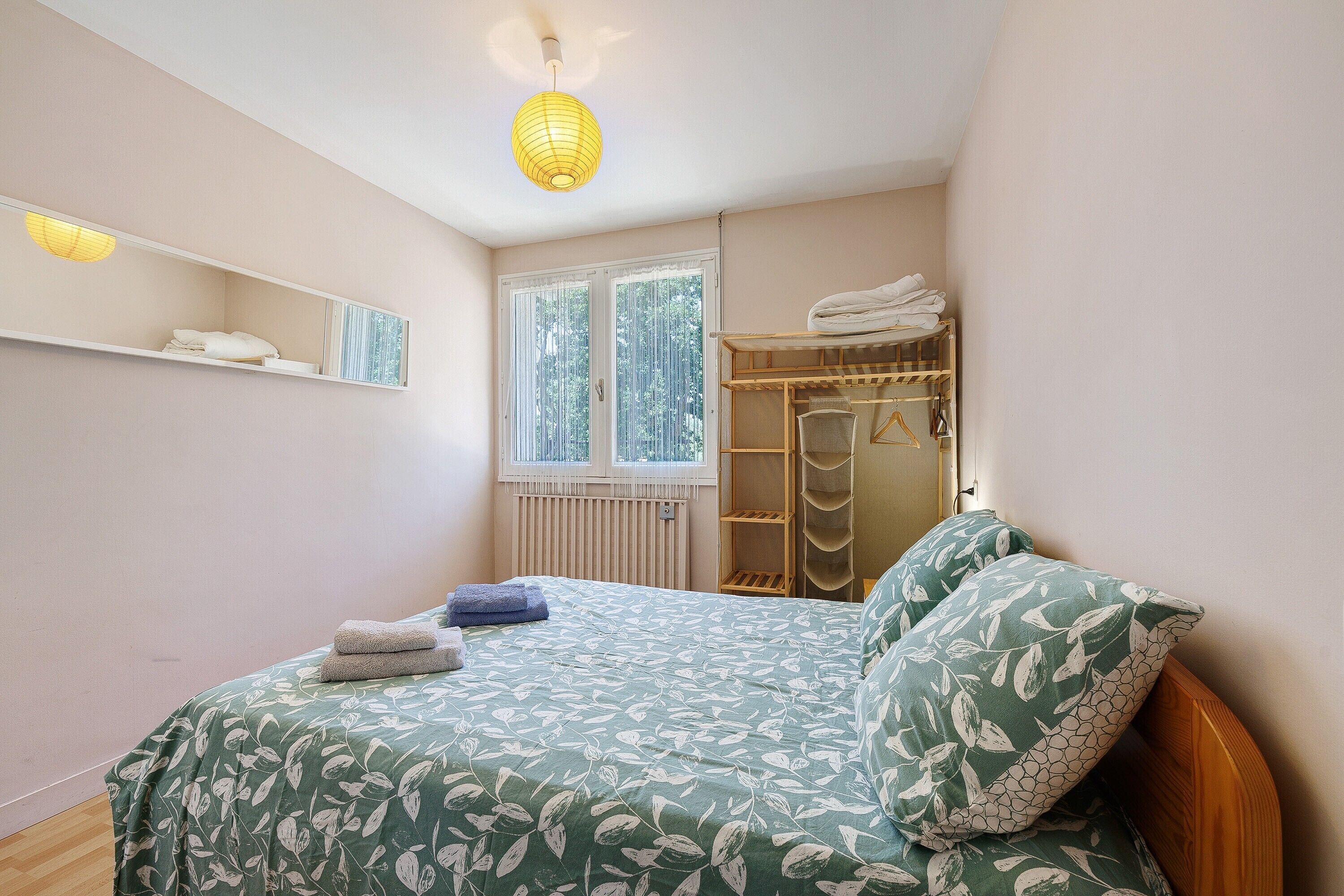 Una camera da letto con un letto, un armadio, uno specchio e una finestra con persiane.