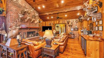 A rustic interior with a fireplace, leather furniture, and deer antlers mounted on the walls.