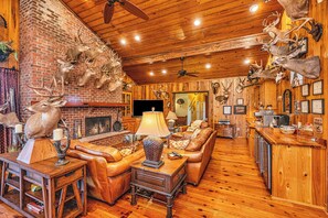 Een rustiek interieur met een open haard, lederen meubels en gewei aan de wanden.