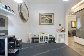 A dining area with a table, chairs, a clock, and a framed painting on the wall. - Carpegna Suite 92 Apartment with Mountain View, Wi-Fi and Air Conditioning (Rome)