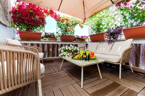 A covered patio area with wicker furniture, a table with drinks and fruit, and potted plants. - Carpegna Suite 92 Apartment with Mountain View, Wi-Fi and Air Conditioning (Rome)