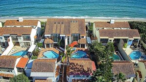 Un complejo turístico con varias edificaciones, piscinas y vista al mar.
