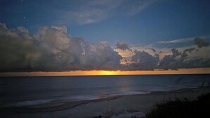 Escena de playa con atardecer y nubes.