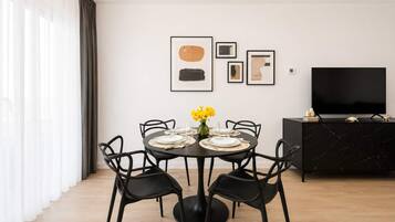 A modern dining room with a round table, black chairs, and a black cabinet with a flat-screen TV.