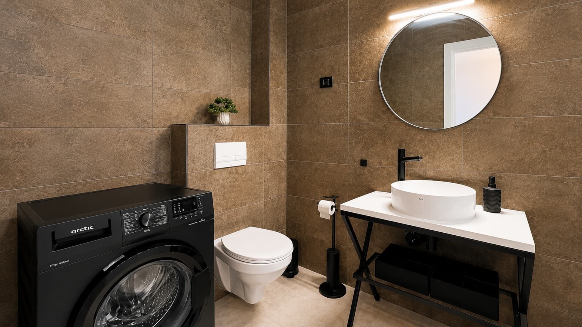 A modern bathroom with a washing machine, toilet, sink, and a mirror.