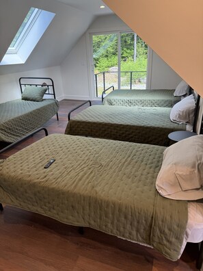 Ein Zimmer mit zwei Betten, einem Dachfenster und einem großen Fenster.