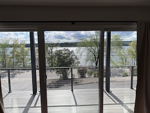 Blick vom Balkon mit Geländer auf ein Gewässer und Bäume.