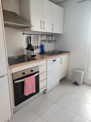 Eine moderne Küche mit weißen Schränken, integriertem Backofen, Geschirrspüler und Spüle aus Edelstahl.
