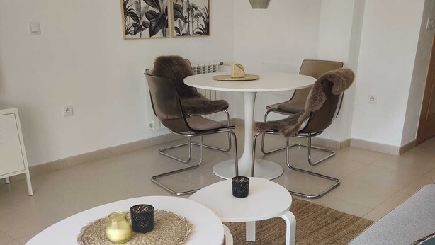 A modern living room with a grey sofa, two white round tables, and a dining area with a white table and chairs. - Exclusive Silent & Sunny Top Floor Apartement, 2 Pools & Golfview (Roldan)
