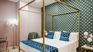 Una cama con dosel, una colcha de diseño geométrico, una mesita de noche con lámpara y una pared con un motivo similar a un abanico.