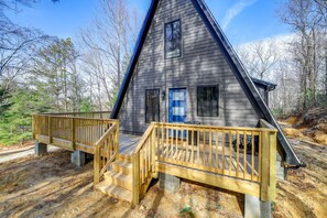 A cabin with a steep roof, a blue door, and a wooden deck leading to the entrance. - Chimney Rock Chalet w Mountain Views Near Main St (Wytheville)