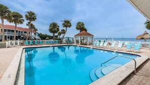 Uma piscina com espreguiçadeiras, um gazebo e palmeiras.