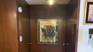 A wooden door with a framed artwork above it, a patterned wooden floor, and a hanging light fixture. - Beautiful Condesa Private Apartment (Ciudad de México)