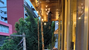 A balcony with hanging decorations, a potted plant, and a view of buildings in the background. - Beautiful Condesa Private Apartment (Ciudad de México)
