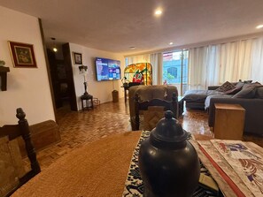 A living room with a wooden floor, a television, a piano, and a sofa. - Beautiful Condesa Private Apartment (Ciudad de México)