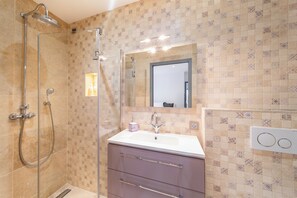 A bathroom with a shower, sink, vanity, and mirror.