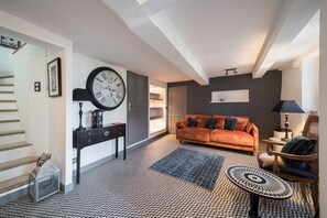 A living room with a sofa, a coffee table, a clock, and a staircase.