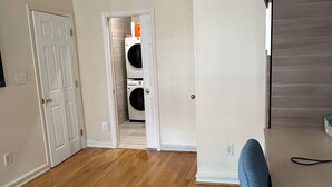 An empty room with hardwood flooring, a door leading to a laundry area, and a television on the wall. - Contemporary 3-Bedroom Rowhouse on Capitol Hill (Washington)
