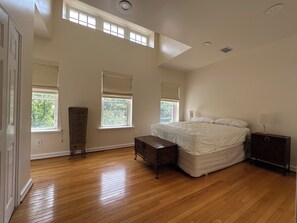 A bedroom with a large bed, a nightstand, a dresser, and a window with a view of trees. - Contemporary 3-Bedroom Rowhouse on Capitol Hill (Washington)