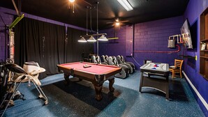 Ein Billardtisch in einem Raum mit violetten Wänden und Deckenventilatoren.