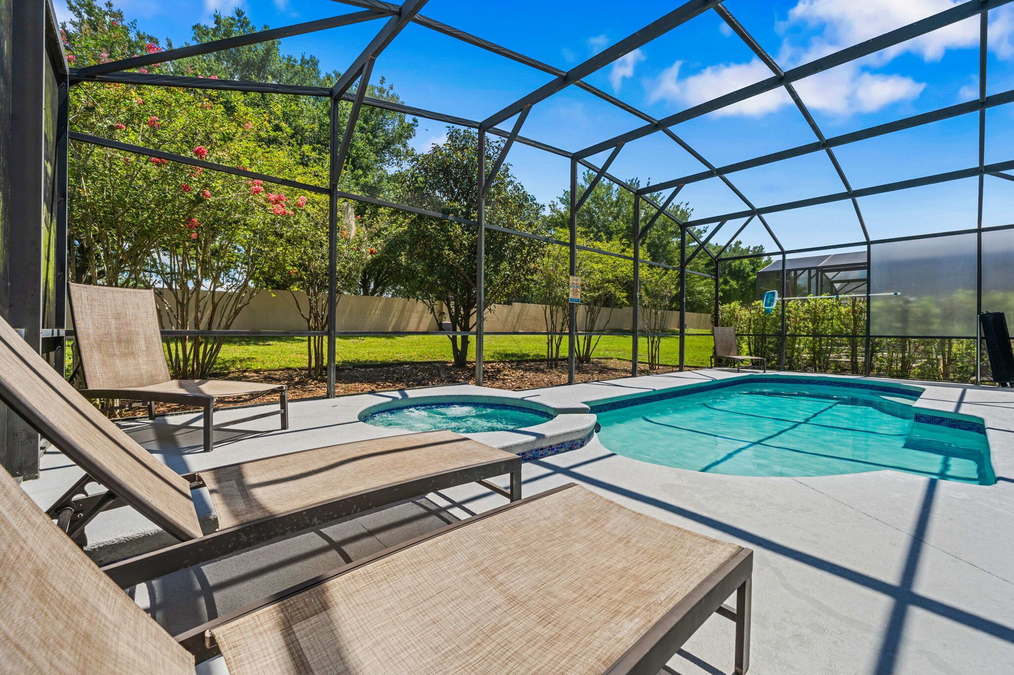 A covered outdoor swimming pool with lounge chairs and a hot tub.