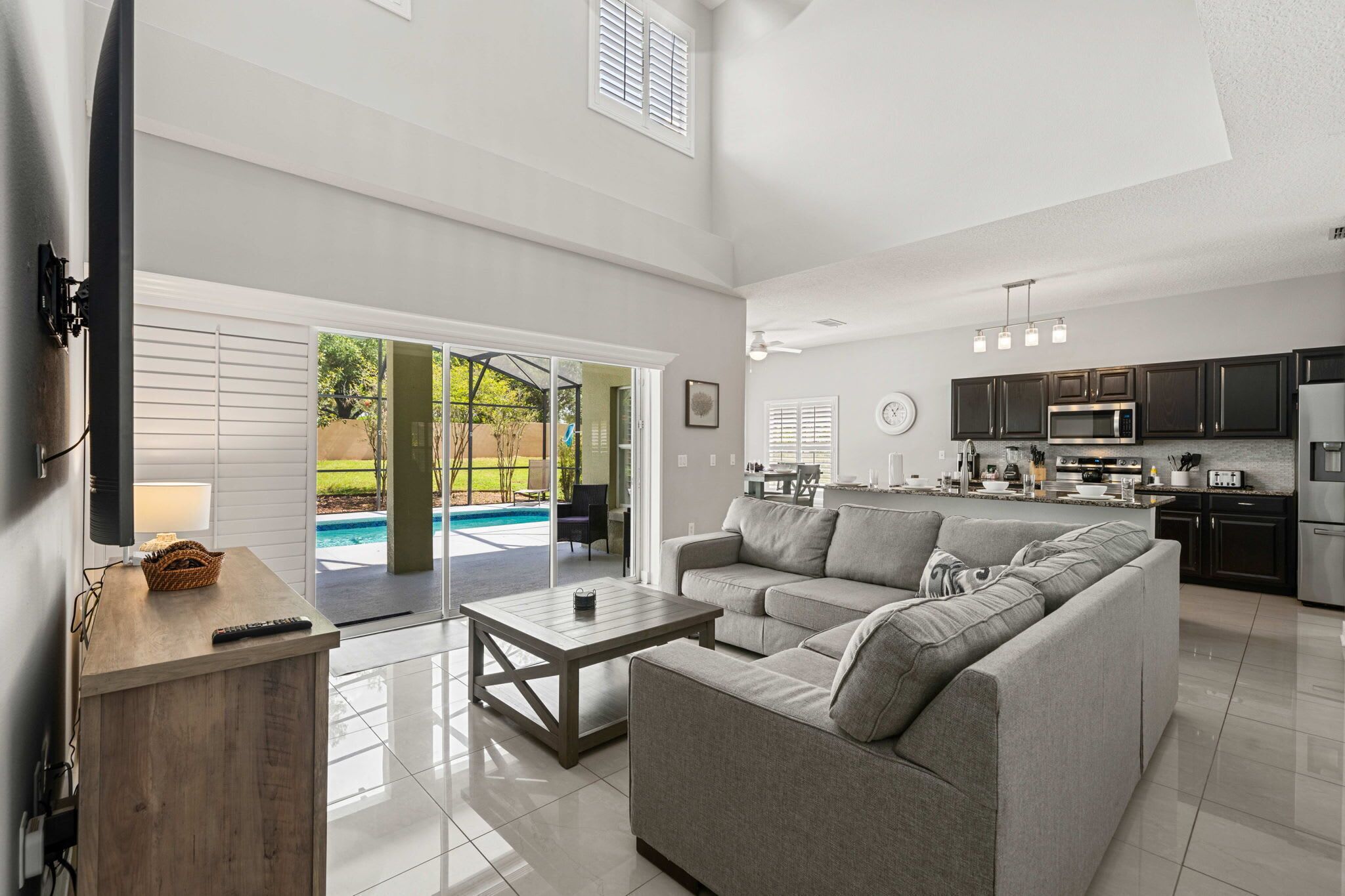 A spacious living area with a large gray sofa, a wooden coffee table, and a TV on a wooden stand.