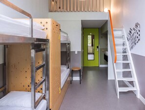 A dormitory room with bunk beds, a small stool, a green door, and a white staircase. - Stayokay Hostel Groningen (Groningen)