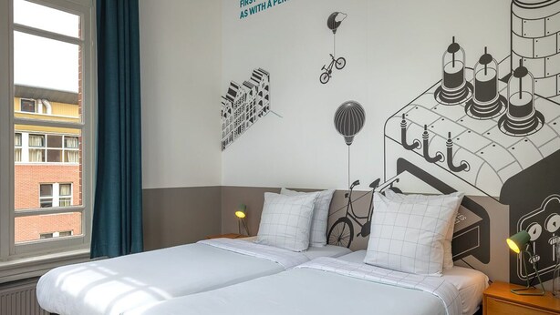 Un letto matrimoniale con biancheria da letto bianca, un comodino con una lampada e un murale raffigurante biciclette e mongolfiere.