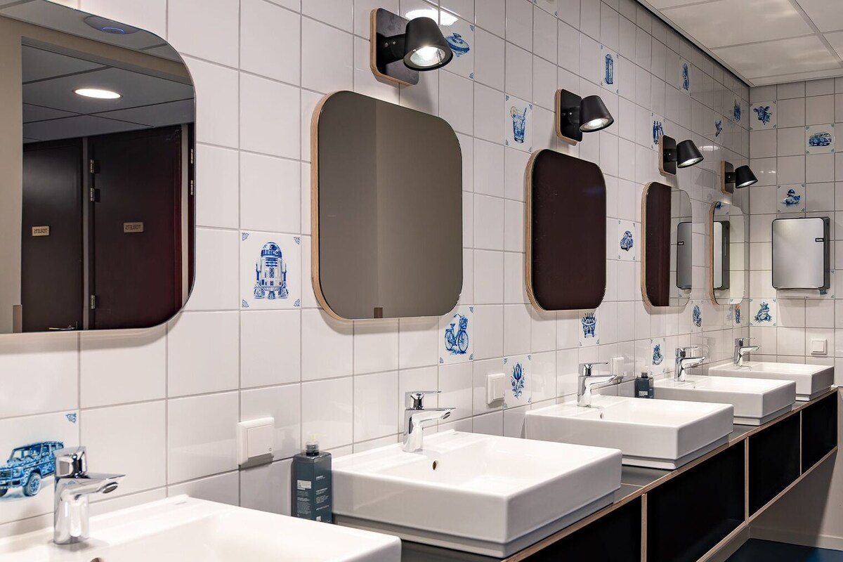 A row of sinks with mirrors and wall-mounted lights in a public restroom.