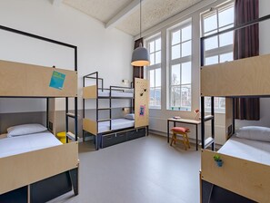 A dormitory room with bunk beds, a desk, a chair, and a hanging light fixture. - Stayokay Hostel Groningen (Groningen)