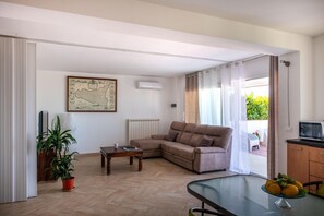 A living room with a sofa, a coffee table, a potted plant, a map on the wall, and a view of the outdoors. - Mondello Sea View (Palermo)