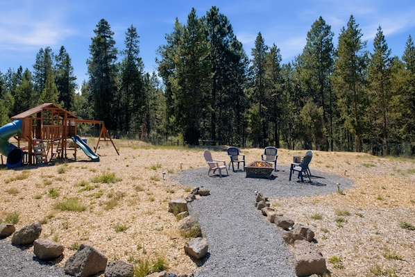 A playground with a slide and swings, surrounded by a forest. - South of Sunriver - Near Mt Bachelor - Hot Tub (Bend)
