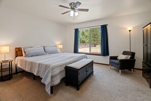 A bedroom with a bed, bedside tables, a bench, a chair, a wardrobe, and a window with curtains. - South of Sunriver - Near Mt Bachelor - Hot Tub (Bend)
