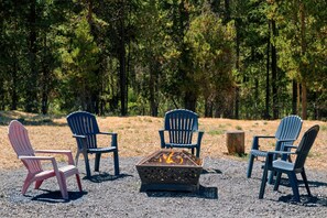 A fire pit surrounded by four Adirondack chairs in a forested area. - South of Sunriver - Near Mt Bachelor - Hot Tub (Bend)