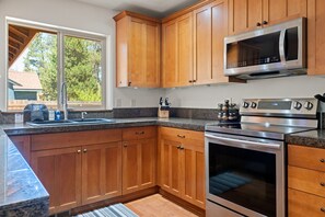 A kitchen with wooden cabinets, a stainless steel oven, a microwave, and a granite countertop. - South of Sunriver - Near Mt Bachelor - Hot Tub (Bend)