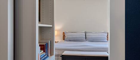 Una camera da letto con un letto, un comodino, una libreria e una ventola a soffitto.