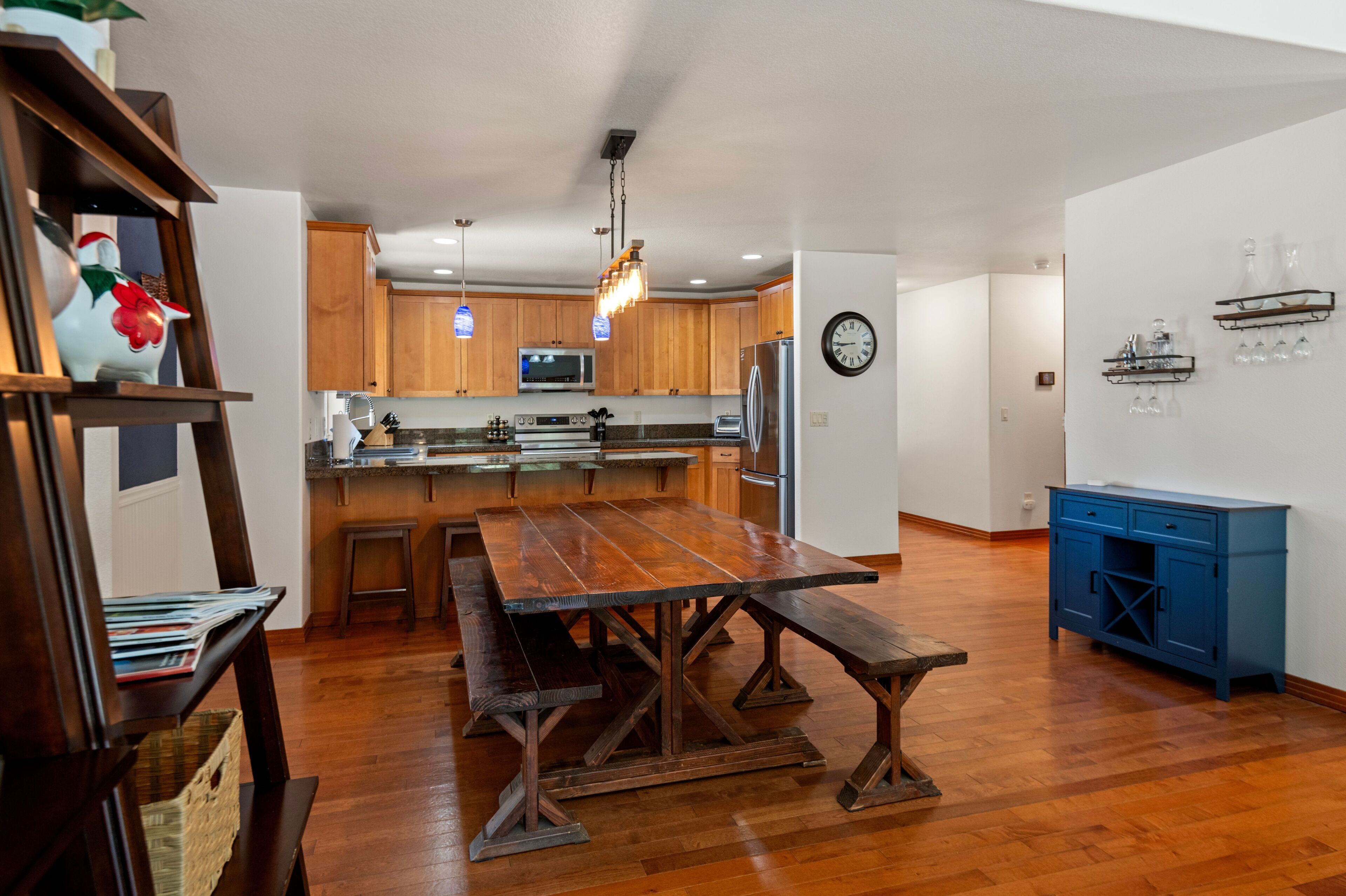 A rustic wooden dining table and benches sit adjacent to the open kitchen.