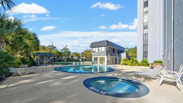 Un espace piscine comprenant deux piscines circulaires, un espace détente couvert et un bâtiment moderne doté d’un toit plat.