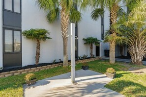 Ein modernes Gebäude mit weißer Fassade, Palmen und einem Betonweg.